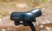 Close-up of a black bike seat with 'Engwe' branding against a blurred natural background.