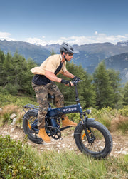 Man riding an electric bike on a mountain trail with scenic mountains in the background