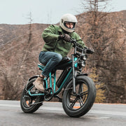 Person riding a motorcycle on a road with mountains in the background