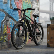 Black electric bike leaning against a graffiti-covered wall.